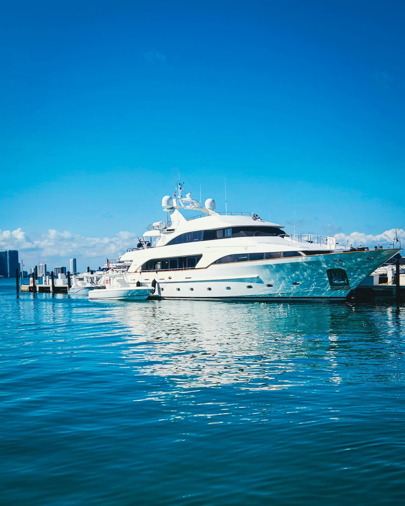 A large white superyacht moored in a marina