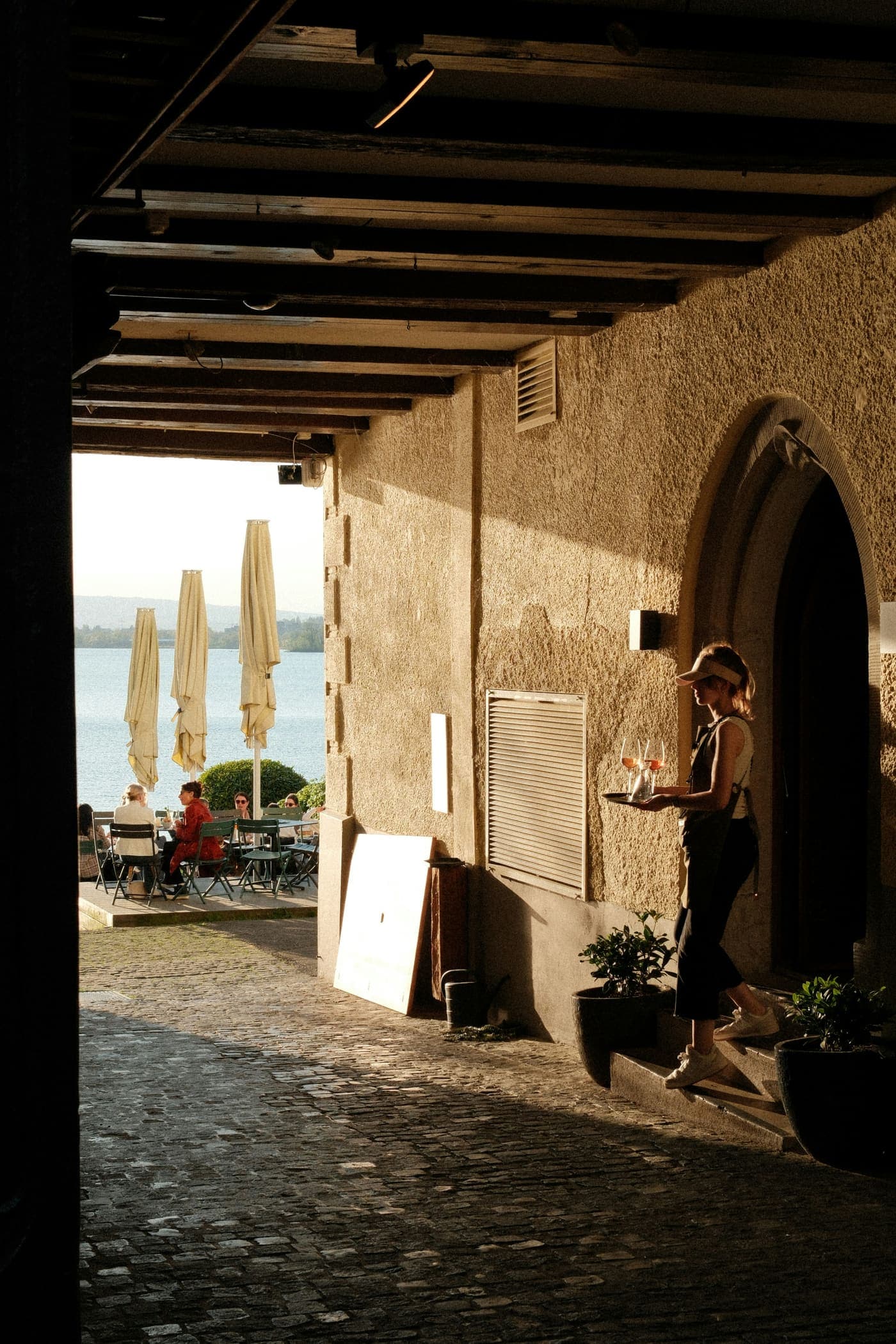 A stewardess carrying a tray of drinks to guests on a waterside terrace
